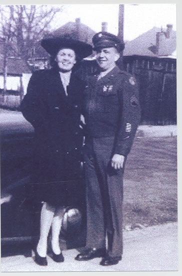 Woman and serviceman standing outdoors together.