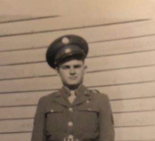 Guy Prichard standing outdoors in a military uniform and peaked cap.