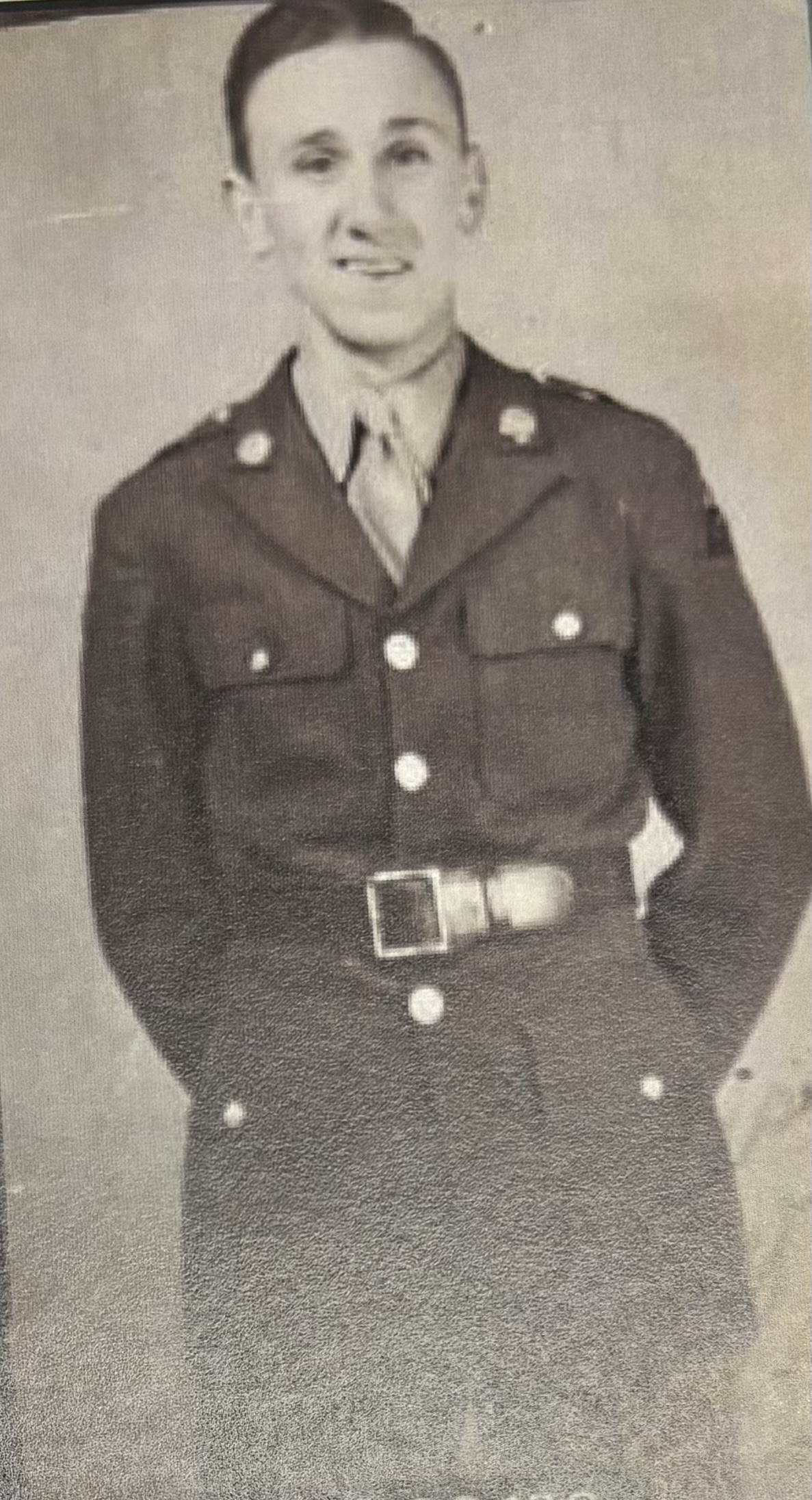 Cropped view of a serviceman wearing a belted military uniform.