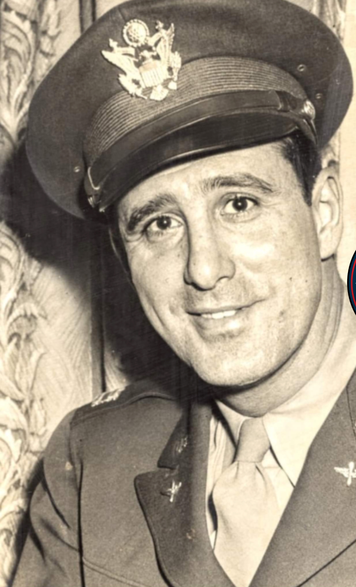 Smiling serviceman wearing a military cap in a close-up portrait.
