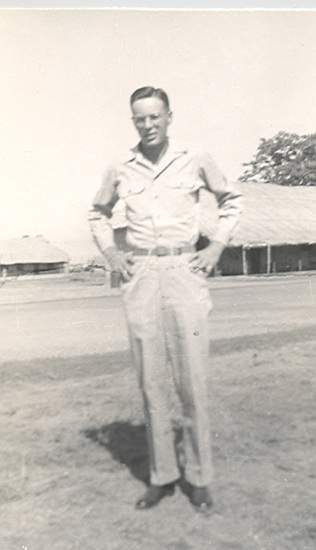 Serviceman standing outdoors in a light-colored military uniform.