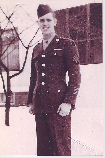 Serviceman standing outside a building in a decorated military uniform.