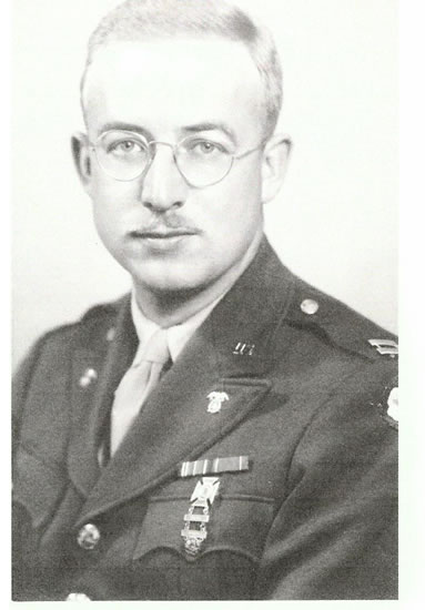 Serviceman wearing glasses and a military uniform in a formal portrait.