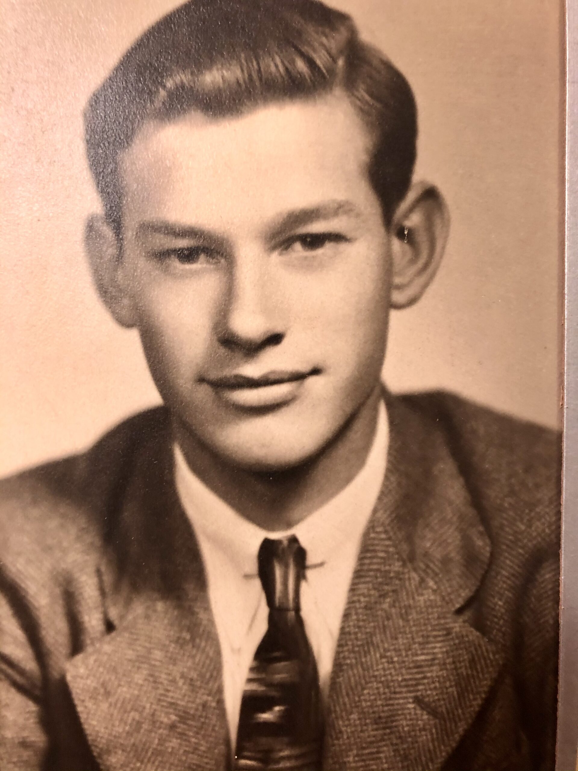 A sepia portrait photograph of a man with dark hair, wearing a tie, posing for a photograph.