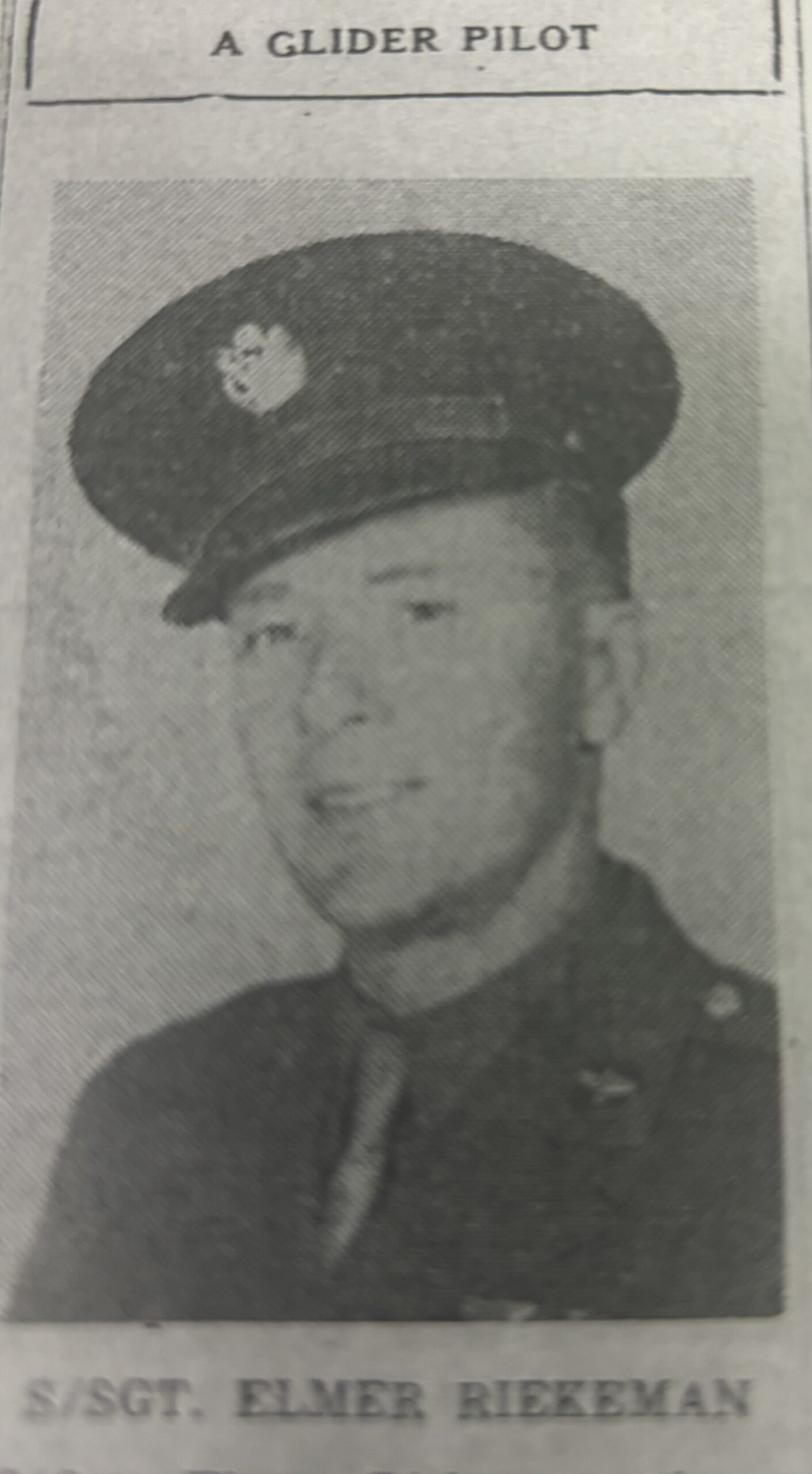 Serviceman wearing a military uniform and peaked cap in a grainy portrait.
