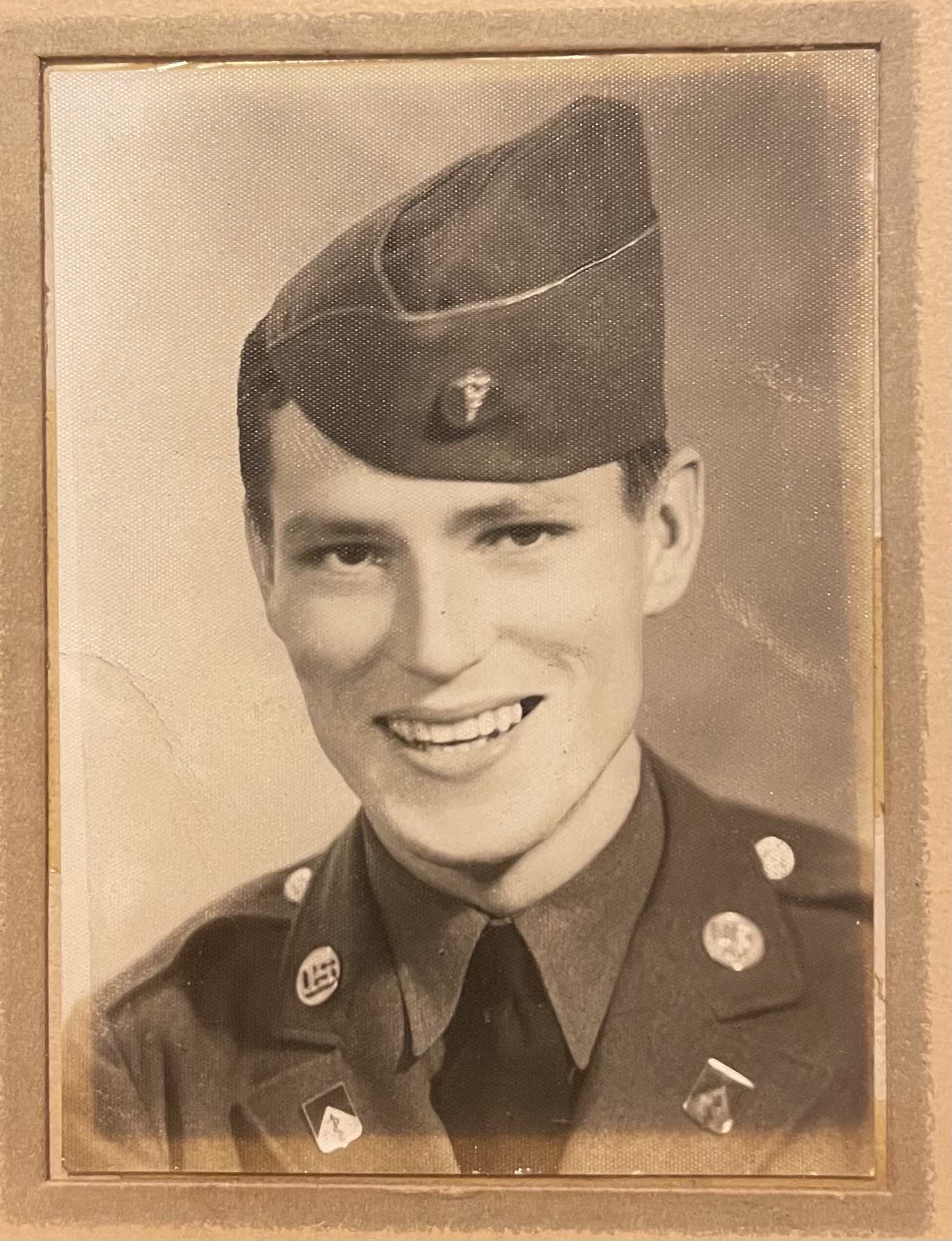 Smiling serviceman wearing a military uniform and garrison cap.
