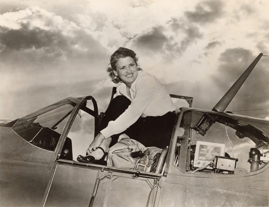 Woman seated in the cockpit of an aircraft.