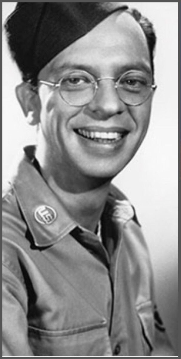 Jesse Don Knots smiling in a close-up black-and-white portrait.