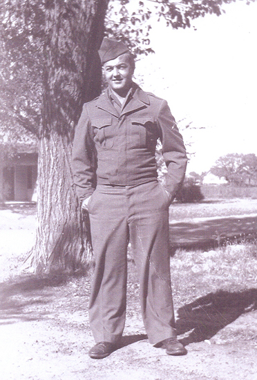 Smiling serviceman standing outdoors in a military uniform.