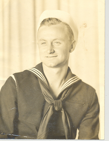 Smiling sailor wearing a dark U.S. Navy uniform.