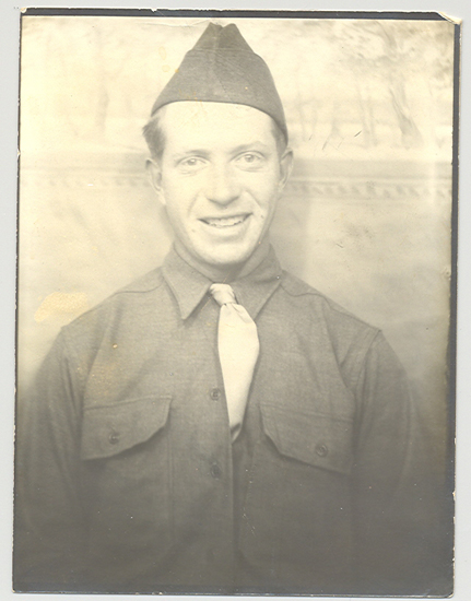 Man in military uniform, smiling at the camera. He is wearing a tie and military cap.