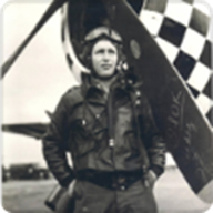 Military pilot wearing flight gear beside a checkered aircraft.