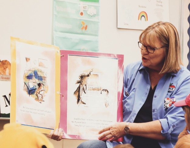 Educator sharing an illustrated book during a classroom activity.