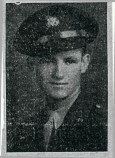 Young serviceman wearing a military cap in a dark portrait.