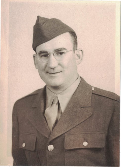 Man wearing glasses, a suit, and a tie in a formal portrait.