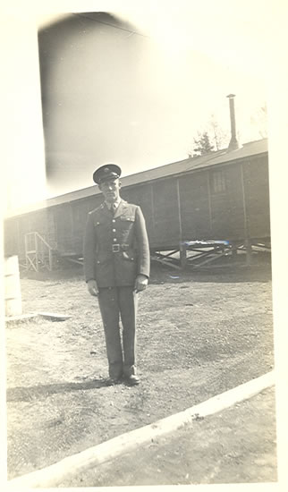 Serviceman standing outdoors beside a military building.