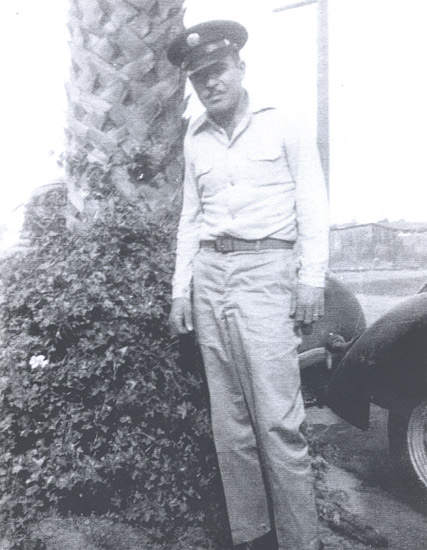 Serviceman standing outdoors in a light-colored military uniform.