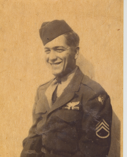 A man in military uniform is standing and smiling at the camera.