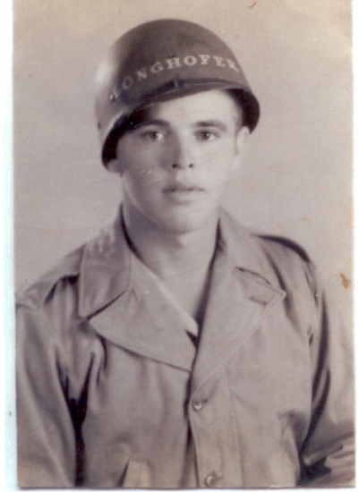 Young serviceman wearing a military field uniform and helmet inscribed Longhofer.