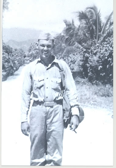 Serviceman standing outdoors in a light-colored military uniform.