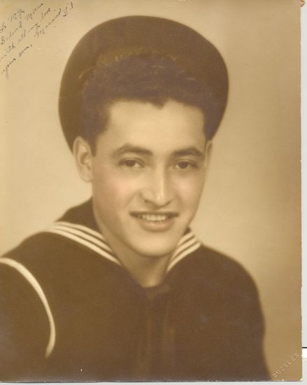 Smiling Macario Gil wearing a U.S. Navy uniform and cap.