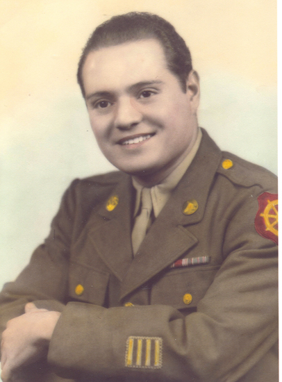 An man in military uniform with medals. He is sitting and smiling at the camera.