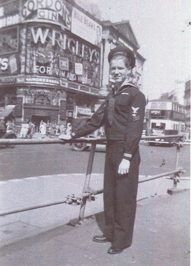 Sailor standing on a city street in a dark naval uniform.