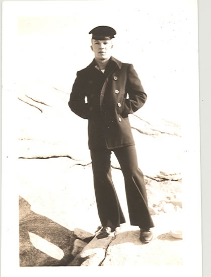 Serviceman standing outdoors in a dark military uniform.