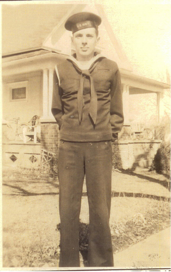 Serviceman standing outside a house in a military uniform.