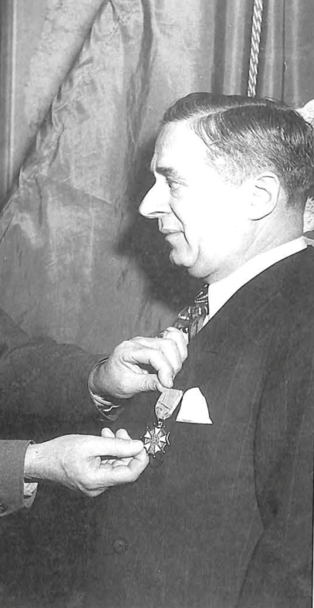 Man shown in profile wearing a dark suit and tie.