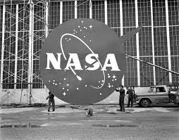 Large NASA insignia displayed outside a building with people standing below.