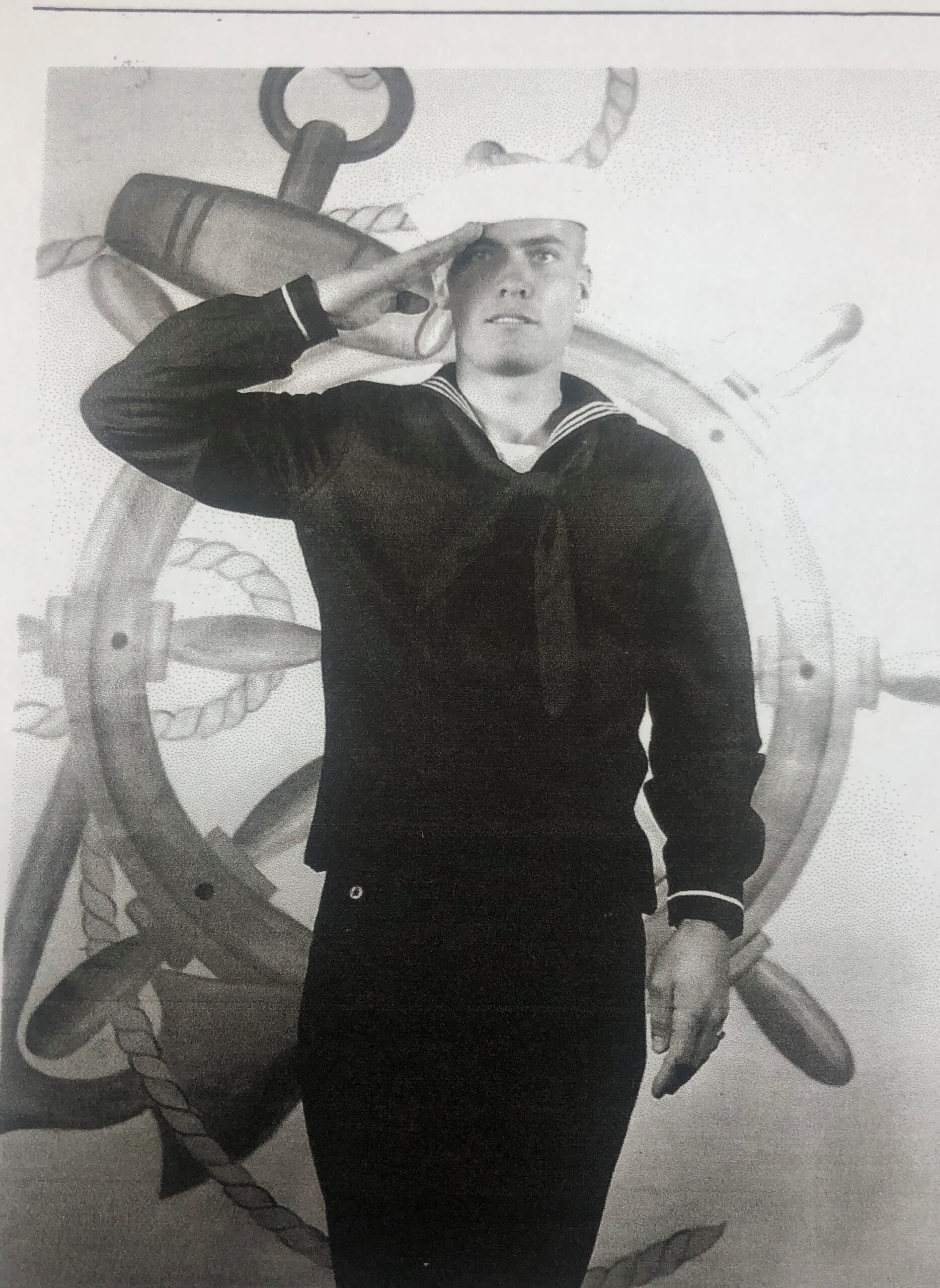 Sailor saluting while standing aboard a ship.