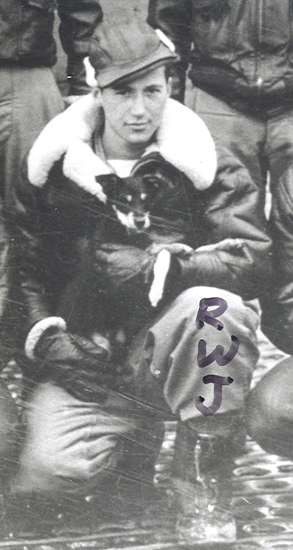 Serviceman seated indoors while holding a dog in his hands.