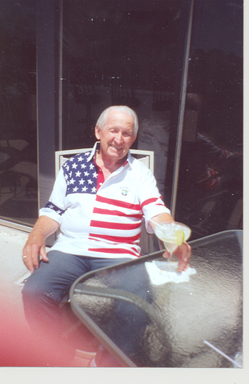 Older veteran seated indoors while holding a framed American flag.