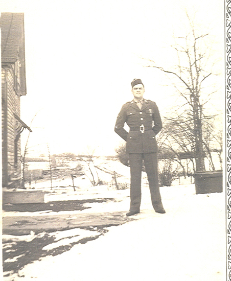 Serviceman standing outdoors in a dark military uniform.