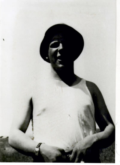Serviceman wearing a white sleeveless shirt and dark military hat.