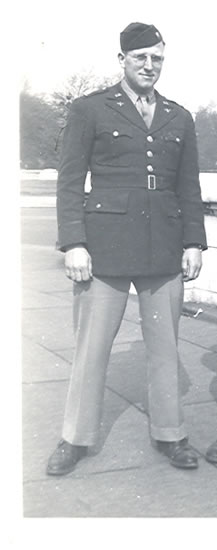 Serviceman standing outdoors in a dark military uniform.