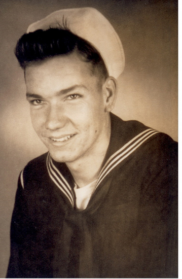 A sepia-toned vintage photograph features a young man in a sailor's uniform with a crew cut and a slight smile, posing for the portrait.