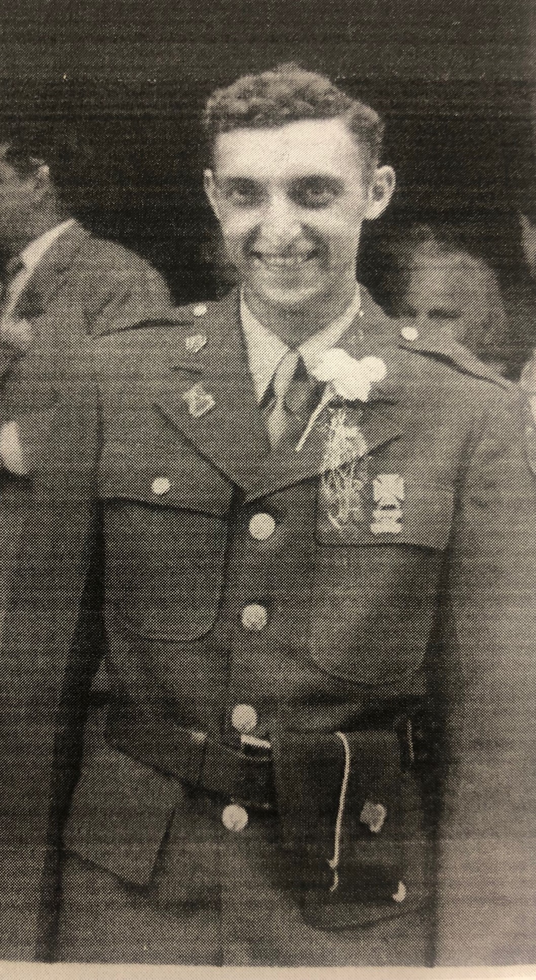 Serviceman wearing a decorated military uniform beside another person.