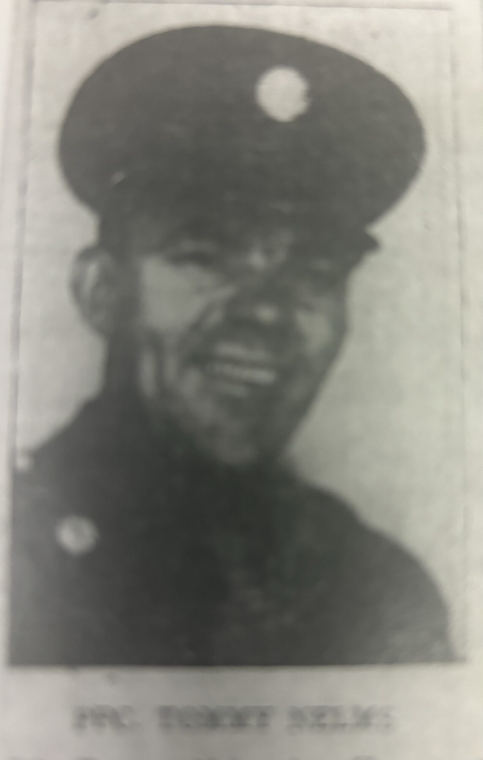 PFC. Tommy Nelms wearing a military helmet in a dark portrait.