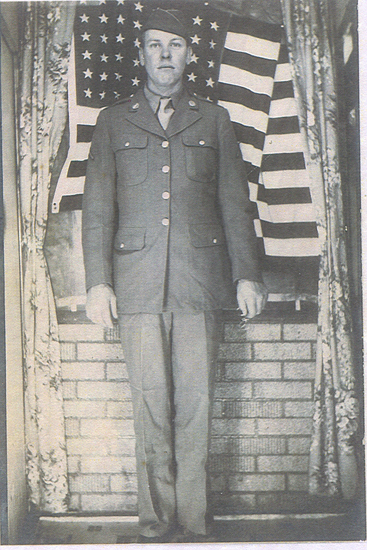 Ted Sanborn standing indoors in a military uniform.