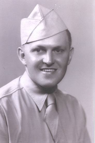 Smiling serviceman wearing a military uniform and garrison cap.