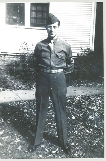 Serviceman standing outdoors with his arm behind his back in a military uniform.