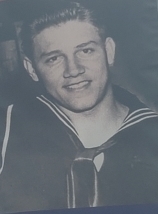 Smiling sailor wearing a dark U.S. Navy uniform.