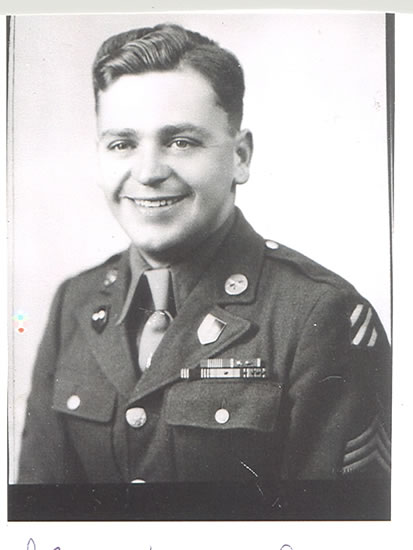 Smiling serviceman wearing a decorated U.S. Army uniform in a black and white portrait.