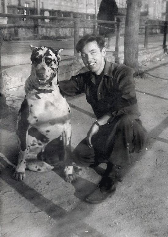 Harry John Walsh crouching outdoors beside a large dog.