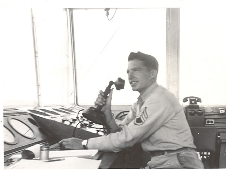Walter L. Hoffman seated indoors while using binoculars.