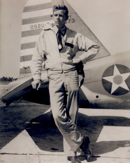 A man poses in front of airplane.