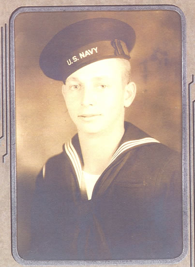 A sepia-toned vintage photograph of a sailor in formal uniform. He is smiling and facing the camera.