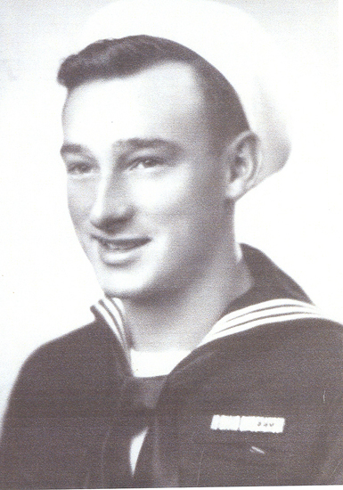 Smiling sailor wearing a dark U.S. Navy uniform.